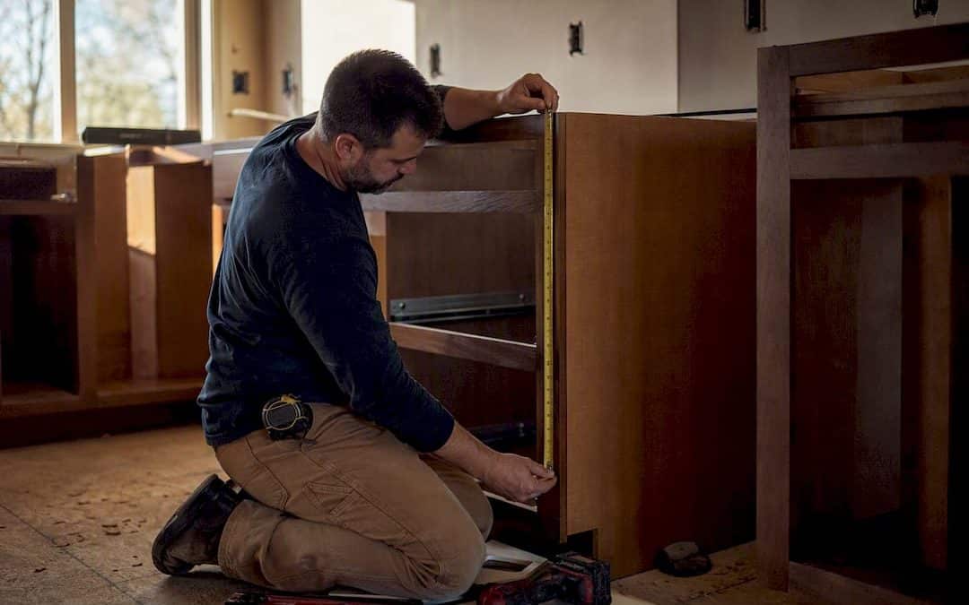 Installer measuring kitchen base cabinet height