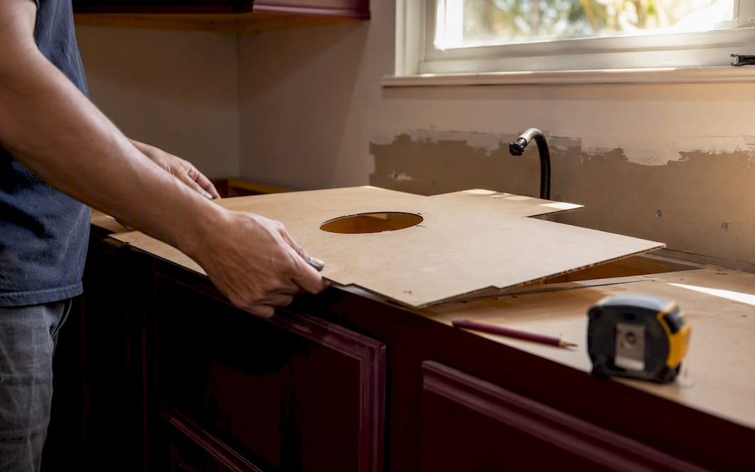 Hands fitting cardboard countertop template on cabinets