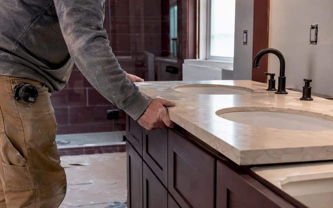 Hands installing quartz countertop in mid-range bathroom